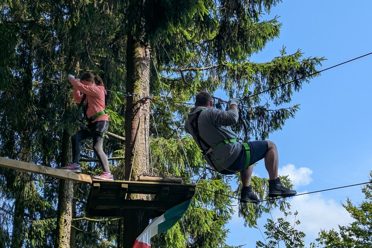 Vater und Tochter im Kletterwald bei Winterberg, an Seilbahn und Kletterplattform