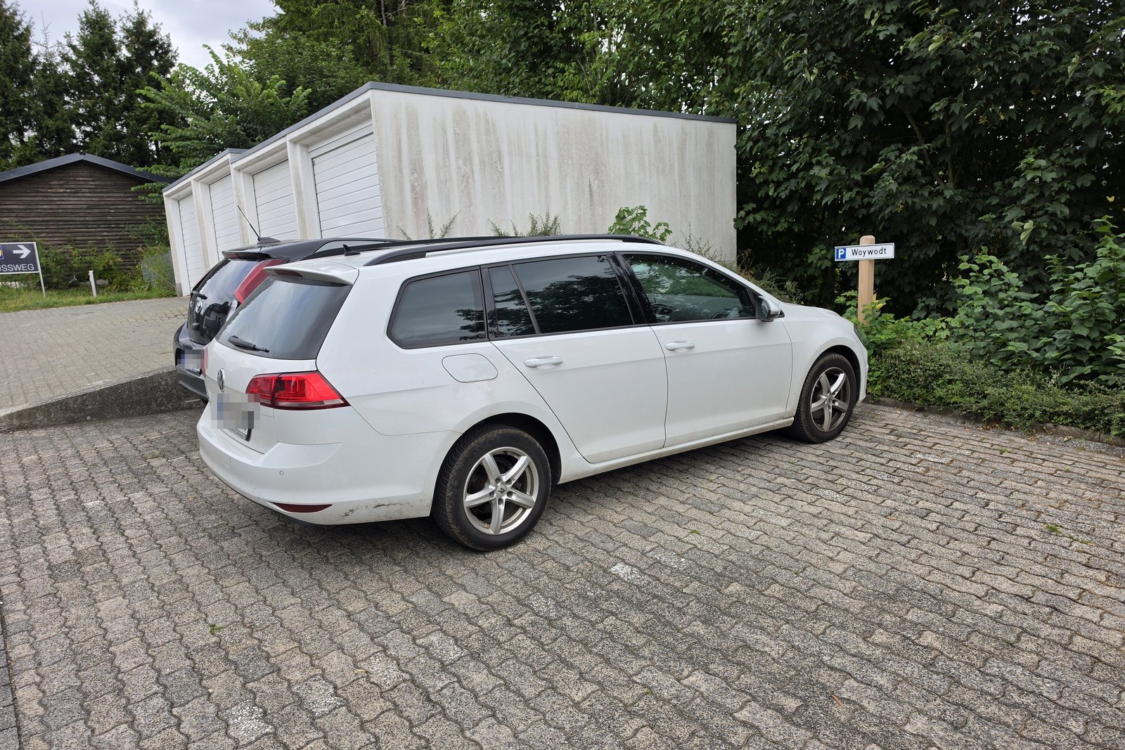 Kombi auf dem kostenlosen Stellplatz der Ferienwohnung in Winterberg, dahinter die Garagen