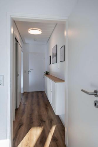 Flur der Ferienwohnung mit weißer Kommode, Bildern an der Wand und Garderobenhaken