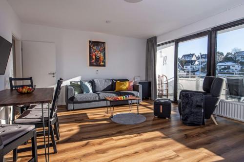 Wohnbereich der Ferienwohnung in Winterberg mit Sofa, Sessel und Zugang zum Balkon