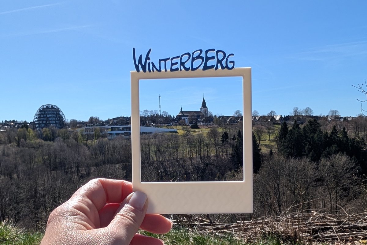 Selbst gedruckter Fotorahmen mit dem Schriftzug Winterberg, dahinter der Ort mit Kirche und Oversum