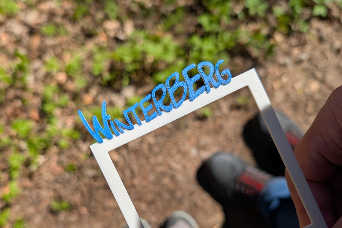 Selbst gedruckter Winterberg-Fotorahmen in der Hand auf einem Waldweg bei Winterberg