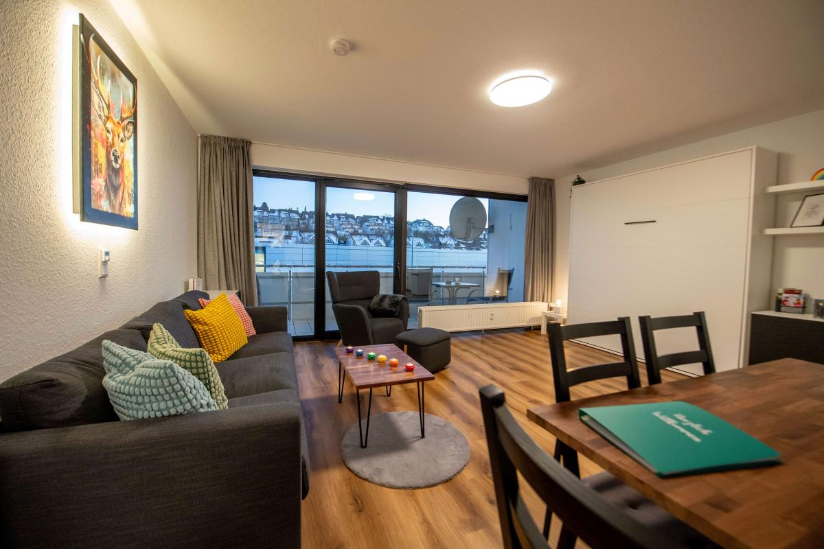 Wohnbereich der Ferienwohnung am Abend mit Sofa, bunten Kissen und beleuchtetem Hirschbild