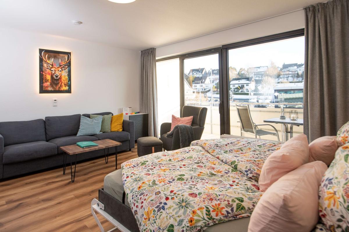 Wohnbereich der Ferienwohnung mit heruntergeklapptem zweitem Doppelbett und Blick zum Balkon